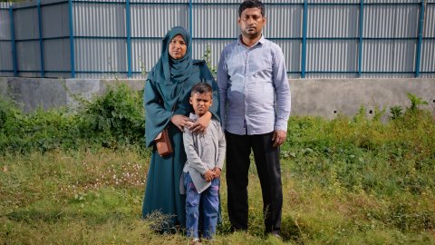 Man, kvinan och barn står på gräset med grå bakgrund och tittar in i kameran.