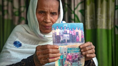 Kvinna visar upp två slitna fotografier.