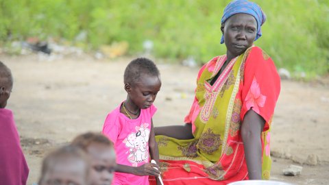 Kvinna sitter på marken tillsammans med sitt barn. 