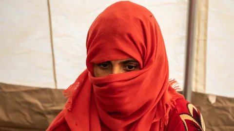 Närbild när en kvinna med röd hijab som tittar neråt.