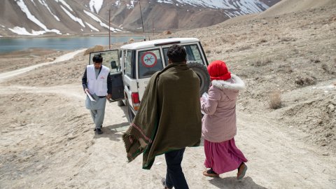 en vit jeep och tre personer på en bergsväg i Afghanistan