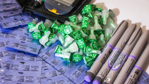 Insulinpennor, nålkapslar och en glukometer ligger på ett bord