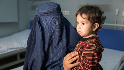 en 11 månader gammal flicka i sitter i sin mammas knä, mamman bär burka