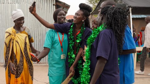 Ett gäng tjejer, vissa i sjukhuskläder, tar en selfie tillsammans.