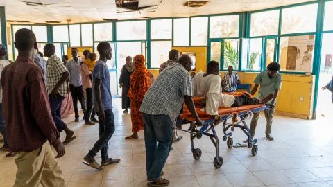 Vårdpersonal skjuter en bår med hjul med en patient på.