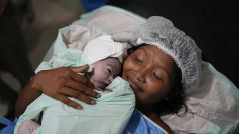 En nybliven mamma håller i sitt nyfödda barn på sjukhuset.