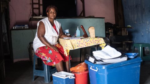 Kvinna sitter vid ett bord och kollar in i kameran. På bordet ligger kondomer.