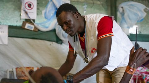 Läkare i Läkare utan gränser väst står böjd över en patient