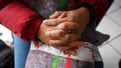 En närbild på ett par knäppta händer över en filt med MSF-tejp