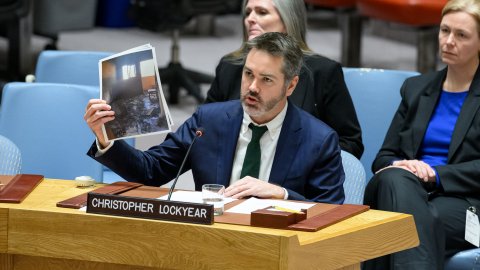 Man i kostym håller upp bilder.