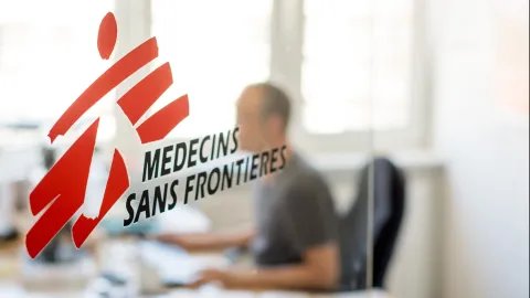 Logotyp med skymtande person bakom.
