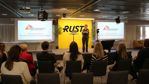 Kvinna står på scen framför publik och berättar om Läkare Utan Gränser.