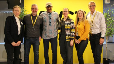 Sex personer från Rusta och Läkare Utan Gränser tittar in i kameran och ler framför Rustas logotyp.