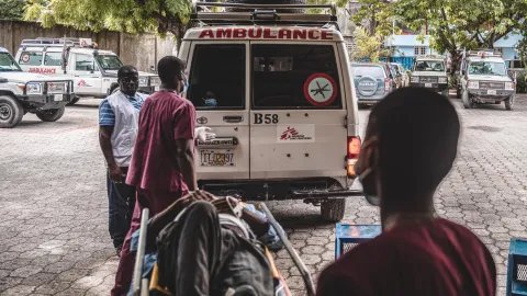 En man på bår bärs in i Läkare Utan Gränsers ambulans. 