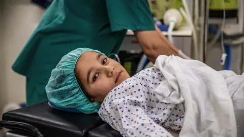 En flicka i sjukhuskläder ligger på en operationsbädd