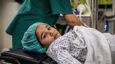 En flicka i sjukhuskläder ligger på en operationsbädd