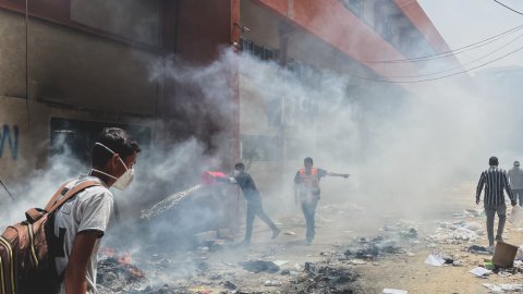 Rök och människor syns i rörig miljö.