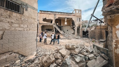 En grupp människor står framför en byggnad som rasat.