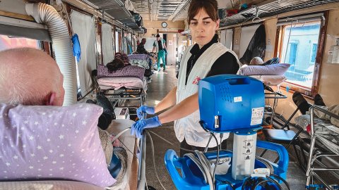 En läkare kontrollerar blodtrycket på en patient i en säng på ett evakueringståg i Ukraina.