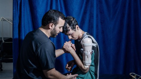 en ung man med svåra brännskador i ansiktet får hjälp av en fysioterapeut