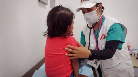 en sjukvårdare lyssnar på en liten flickas andningsljud på en hälsoklinik