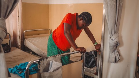 Gravid kvinna lutar sig framåt mot sjukhussäng.