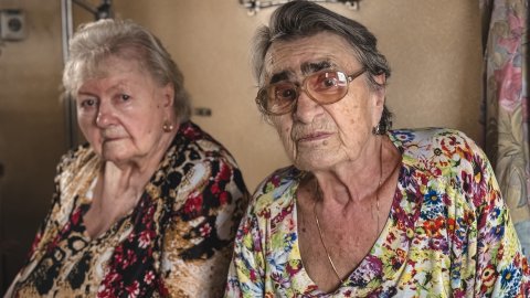 Två äldre kvinnor tittar in i kameran och ser bekymrade ut.