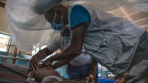 en sjukvårdare undersöker ett barn som ligger i en sjukhussäng