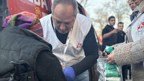 en läkare i vit väst behandlar ett sår på en kvinnas arm