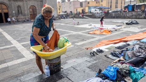 En kvinna tvättar kläder i en balja på ett torg i Mexico City.