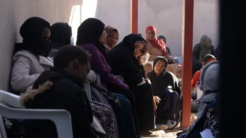 En grupp kvinnor sitter väntandes i en lång kö.