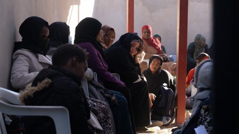 En grupp kvinnor sitter väntandes i en lång kö.