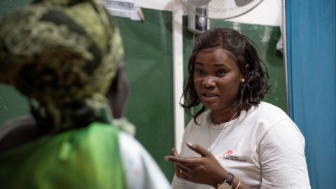 En kvinna i Läkare Utan Gränser-tröja sitter framför en kvinna i grönt med ryggen mot kameran.