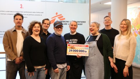 En grupp glada personer håller i en check där det står 24 miljoner