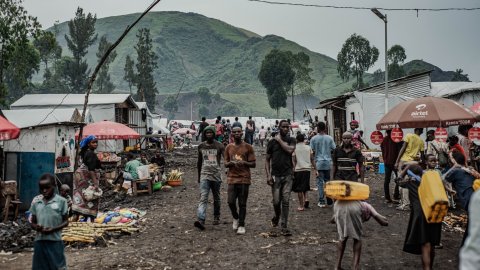 Människor på en marknad framför höga berg.