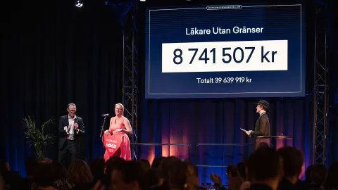En kvinna tar emot en gåva från två män på en scen under en gala