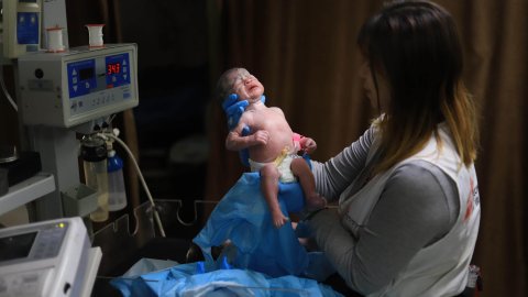 Kvinna i msf-väst håller ett nyförlöst barn i sjukhusmiljö