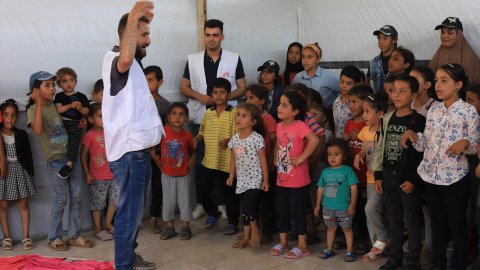 Man i MSF-väst håller händerna över huvudet inför hänförda barn