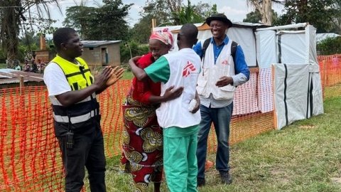 Glada personer kramas utanför ett oreange staket