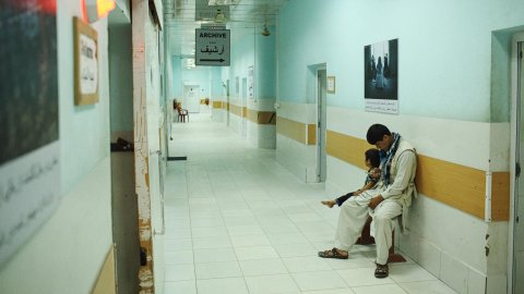 Ett barn sitter tillsammans med en man i en sjukhuskorridor