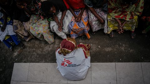 En kvinna med Läkare Utan Gränser-väst sitter med ryggen mot kameran framför en grupp kvinnor vars ansikten inte syns.