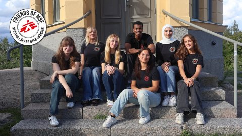 En grupp unga människor sitter på en stentrappa i Friends of MSF-tshirts 