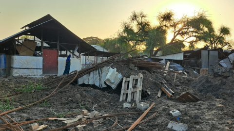 En skadad byggnad med högar med bråte utanför.