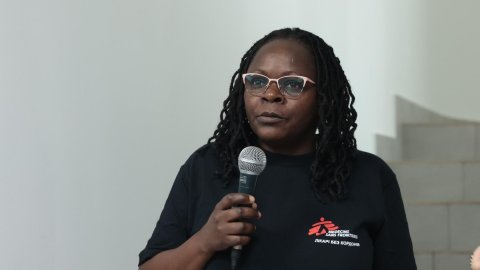 En kvinna med Läkare Utan Gränser-tshirt som håller i en mikrofon.