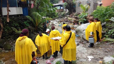 En grupp gulklädda människor utomhus i regn och lera.