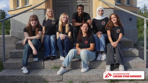 En grupp unga människor sitter på en stentrappa i Friends of MSF-tshirts 