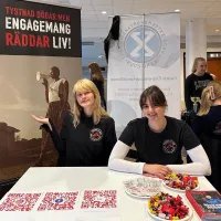 Två unga kvinnor i Friends of MSF-tshirts bakom ett bord på en mässa