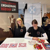 Två unga kvinnor i Friends of MSF-tshirts bakom ett bord på en mässa