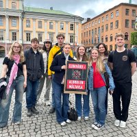 En grupp ungdomar i stadsmiljö som håller ett plakat med texten Sjukvård aldrig en måltavla