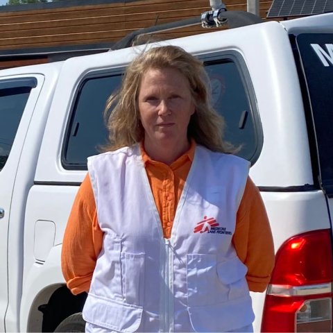 Kvinna tittar in i kameran, har på sig Läkare Utan Gränsers väst